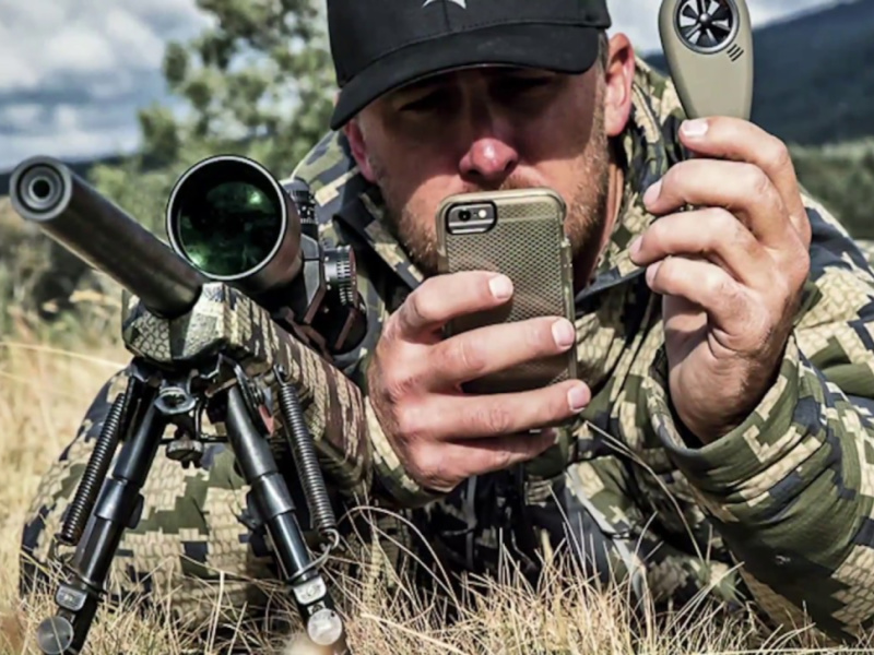 hunter looking at geoballistics app, prone with rilfe that has a Vortex scope.